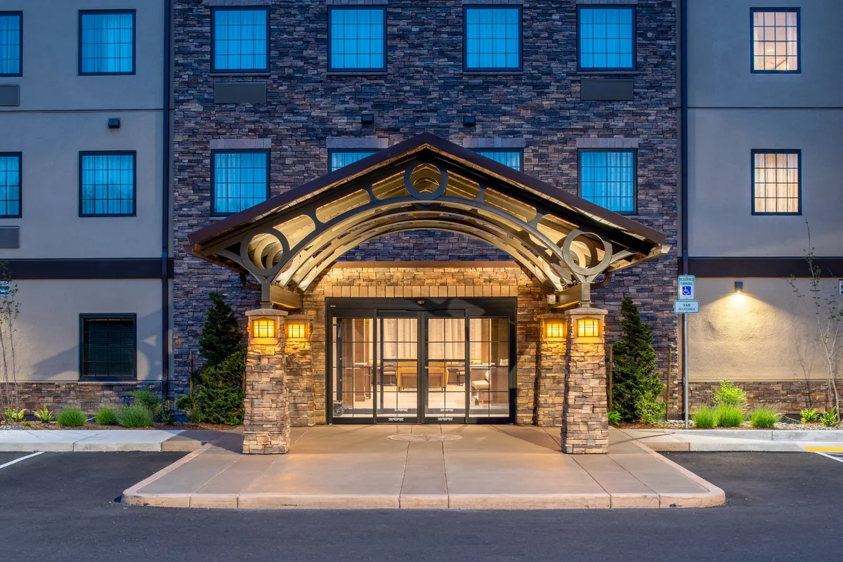 The image showcases the arched entrance and stone facade of the hotel, illuminated with warm outdoor lighting. The entryway suggests a safe, inviting, and accessible starting point for families heading out to or returning from local attractions.